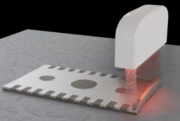 A white machine prints a circuit onto a metal surface using a red laser in a process demonstration.