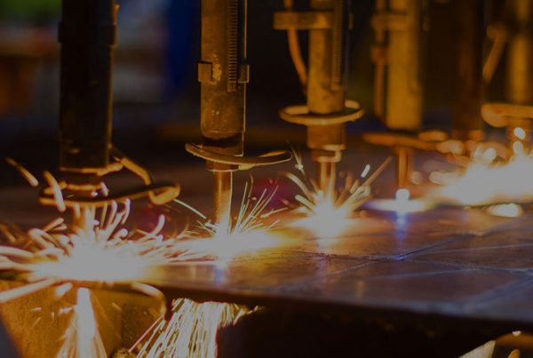 Automated welding machines operating on a 3D metal printing assembly line, emitting sparks during the manufacturing process.