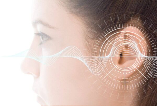 Close-up side view of a person's ear with a series of digital waveforms and circular diagram overlays, implying a concept related to hearing or audio technology.