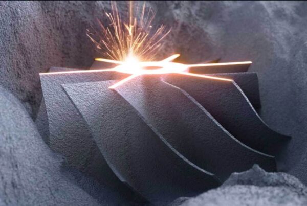 A metal object with a complex geometric shape is being worked on by a laser, emitting sparks in an industrial setting.