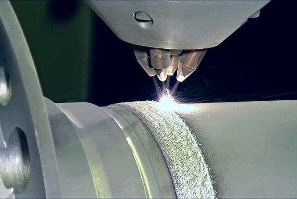 Close-up of a laser cutting machine precisely engraving a pattern on a cylindrical metal object, showcasing the integration of DED additive manufacturing for enhanced precision.