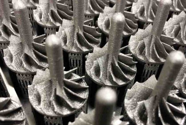 Close-up view of a group of machined metal turbine blades arranged in rows, showcasing intricate engineering details and symmetrical design, with careful printing on metal surfaces enhancing the precision and functionality.