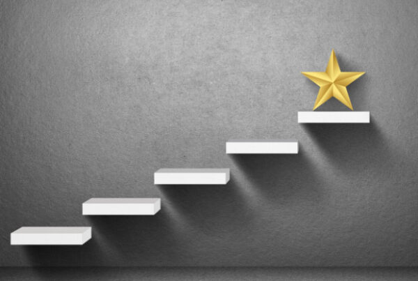 A gray wall with a set of white ascending steps displays a golden star on the topmost step.