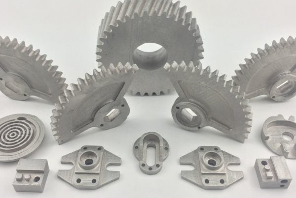 A collection of various metal mechanical components, including gears, brackets, and other precision parts, displayed on a white background.