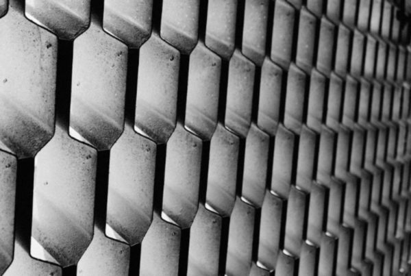 Black and white close-up of a textured wall featuring a repeating pattern of hexagonal shapes.