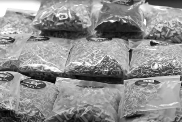 Black and white image of several transparent bags filled with various types of pasta on a table.