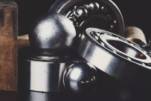 Close-up shot of assorted metal bearings and balls on a dark surface.