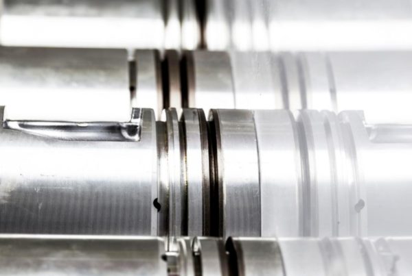 Close-up view of polished cylindrical metal components with precision grooves and cuts, arranged in parallel alignment.