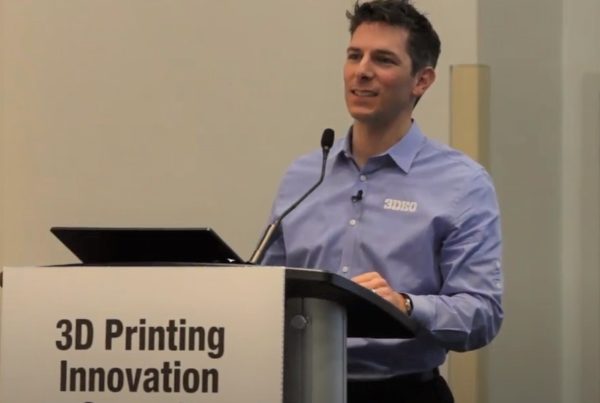 A man in a blue shirt speaking at a podium labeled "3d printing innovation summit.