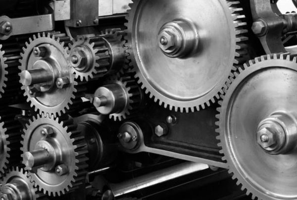 Black and white photo of interlocking metal gears and cogs, showcasing intricate mechanical details.