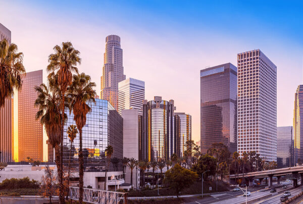 Panoramic view of a cityscape with tall modern buildings, palm trees, and an empty highway in the foreground during a rapid sunset just like what you might see at TCT 2024.