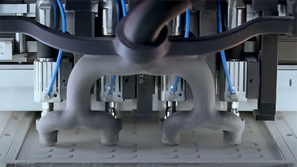 A close-up of a 3D printer in operation, with multiple nozzles extruding material onto a flat surface, showcasing the precision of 3D printing metal components.