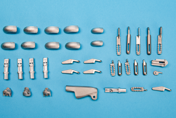 Assorted small metal components, ideal for 3D printing, are meticulously arranged in rows on a blue background.