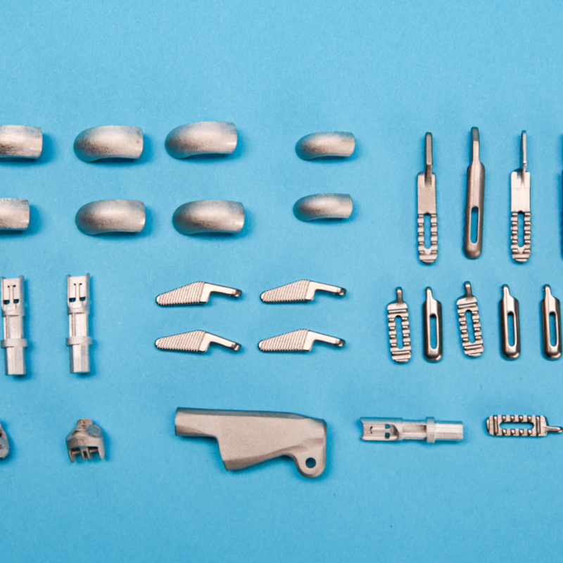 Assorted small metal components, ideal for 3D printing, are meticulously arranged in rows on a blue background.