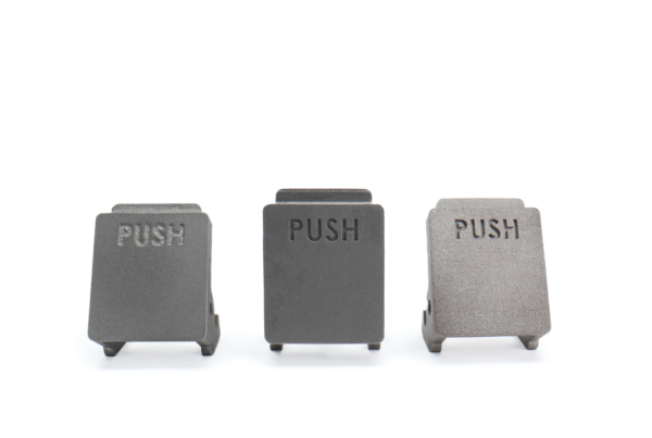 Three black metal push buttons, each labeled "PUSH," are arranged side by side on a white background, illustrating a sleek example of hybrid assembly design.