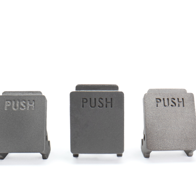 Three black metal push buttons, each labeled "PUSH," are arranged side by side on a white background, illustrating a sleek example of hybrid assembly design.